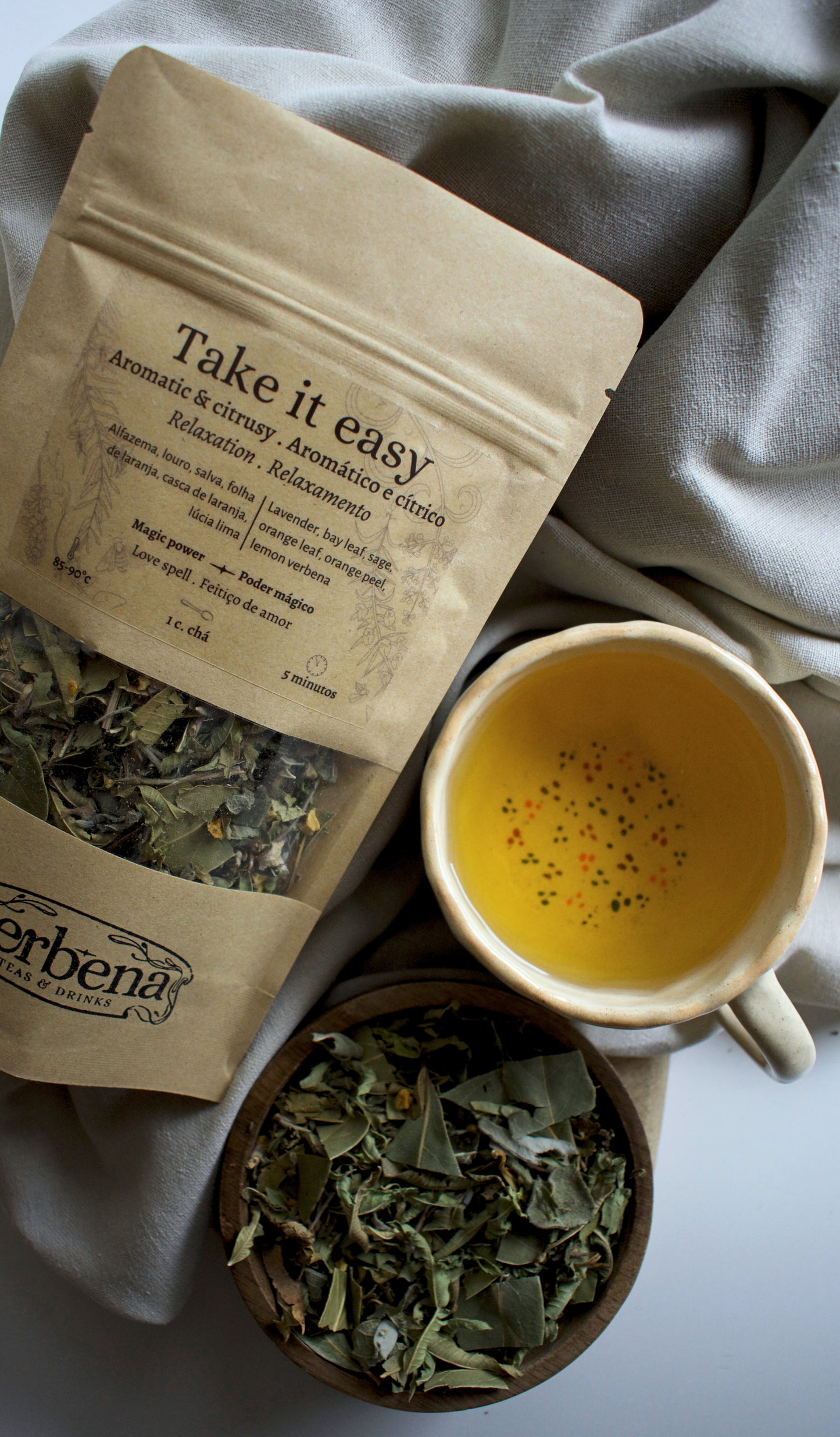 Tea packaging labeled 'Take it easy' with a cup of tea and a bowl of tea leaves on a soft fabric background.