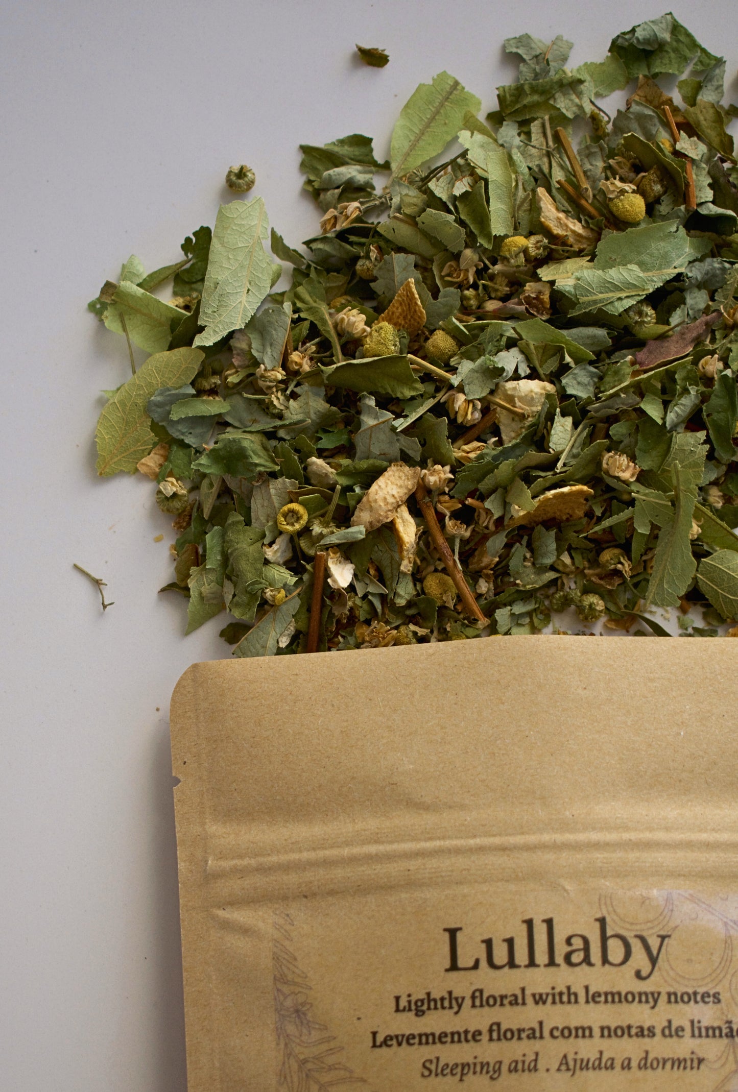 Dried herbs on a white surface with a Lullaby tea packaging.