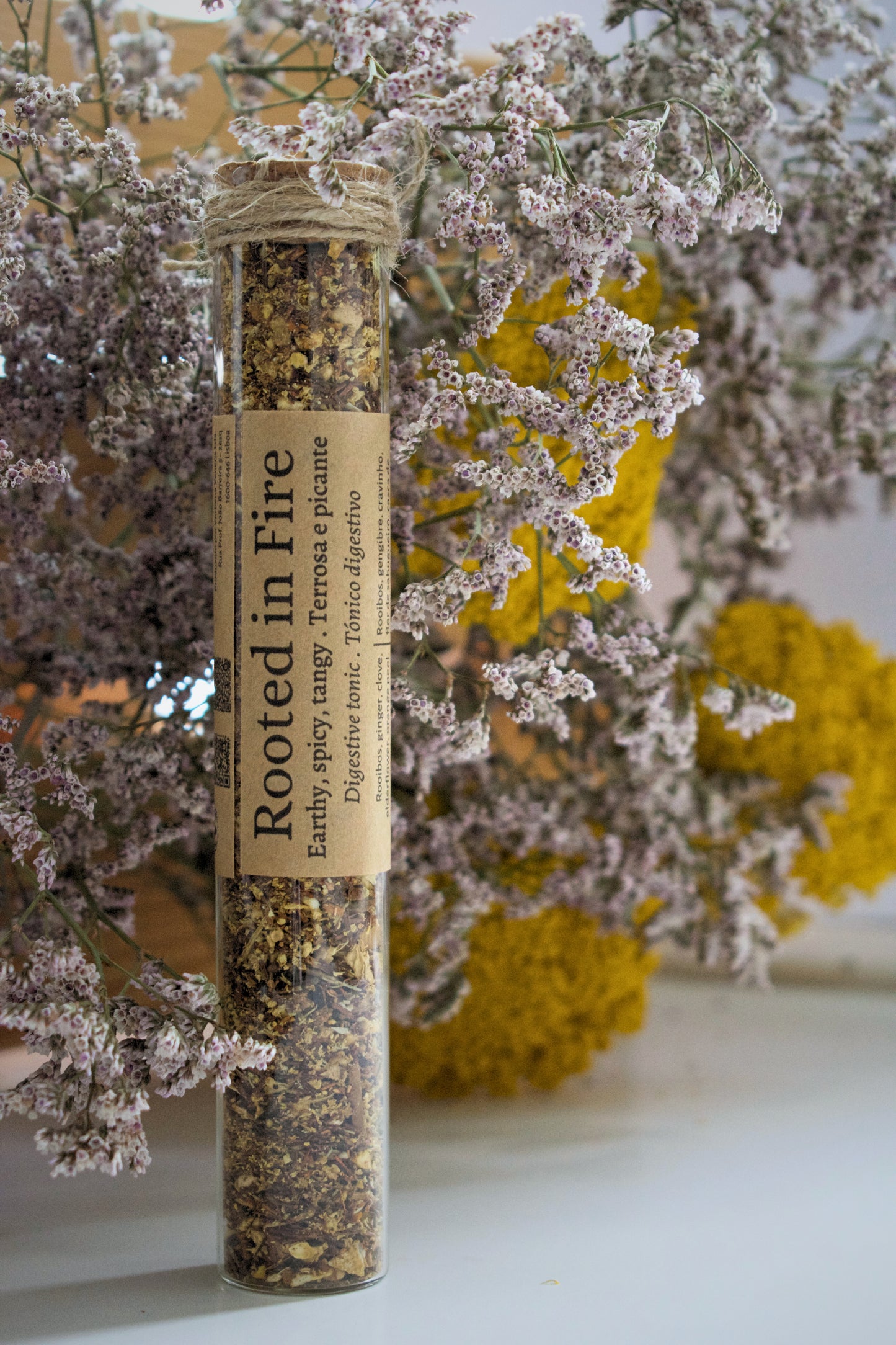 Glass tube with Rooted in fire on floral background.