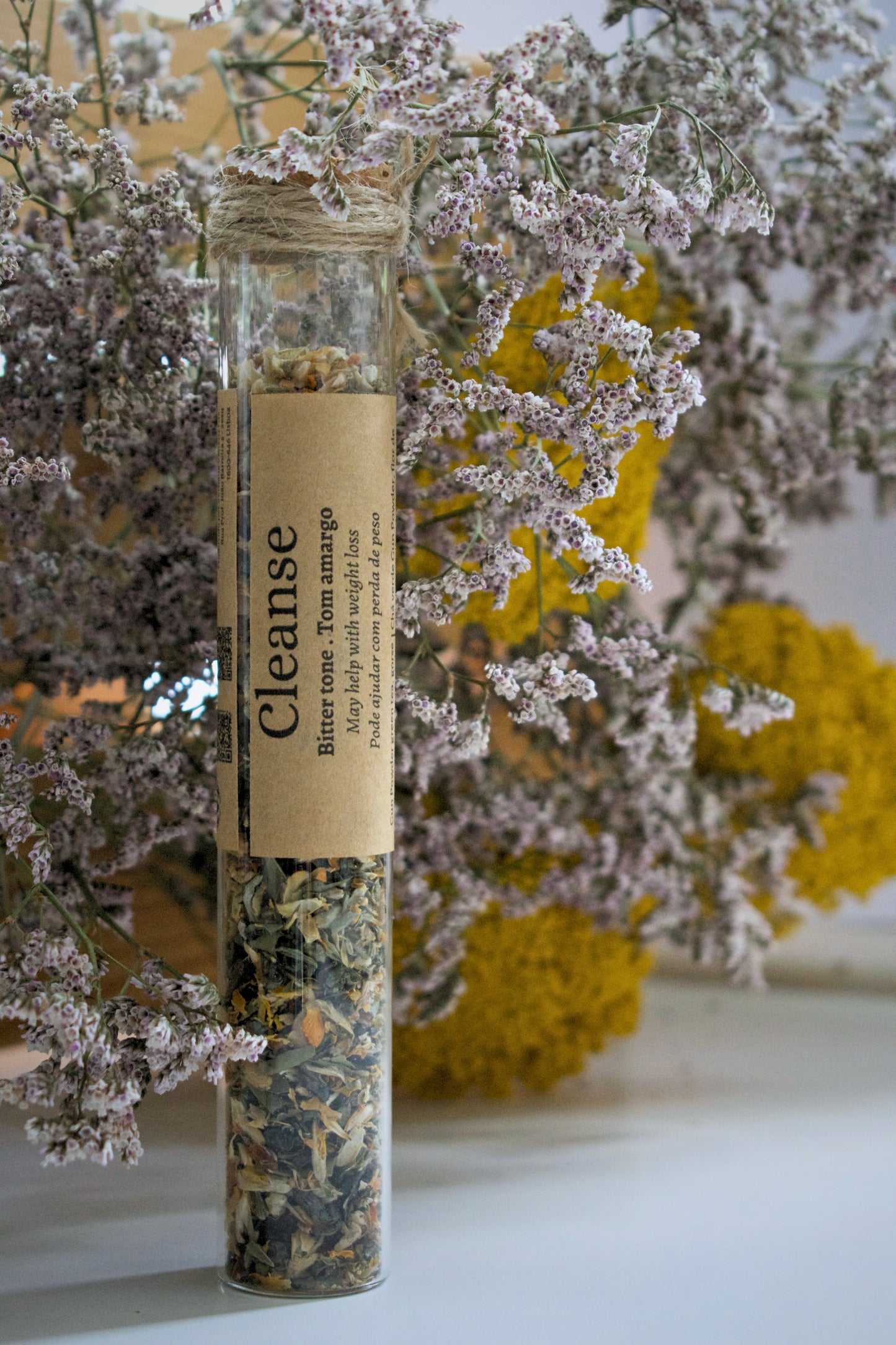 Glass tube with Cleanse tea blend, a kraft label with information is wrapping the tube.