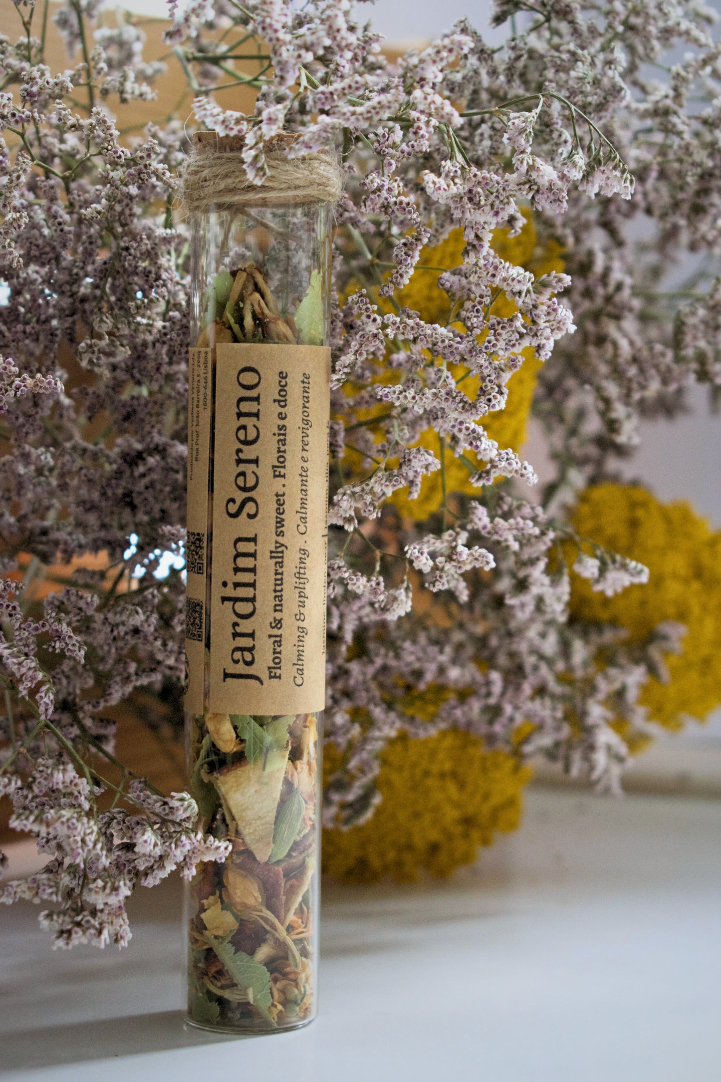 Jardim Sereno loose leaves tea in a glass tube on a floral background.
