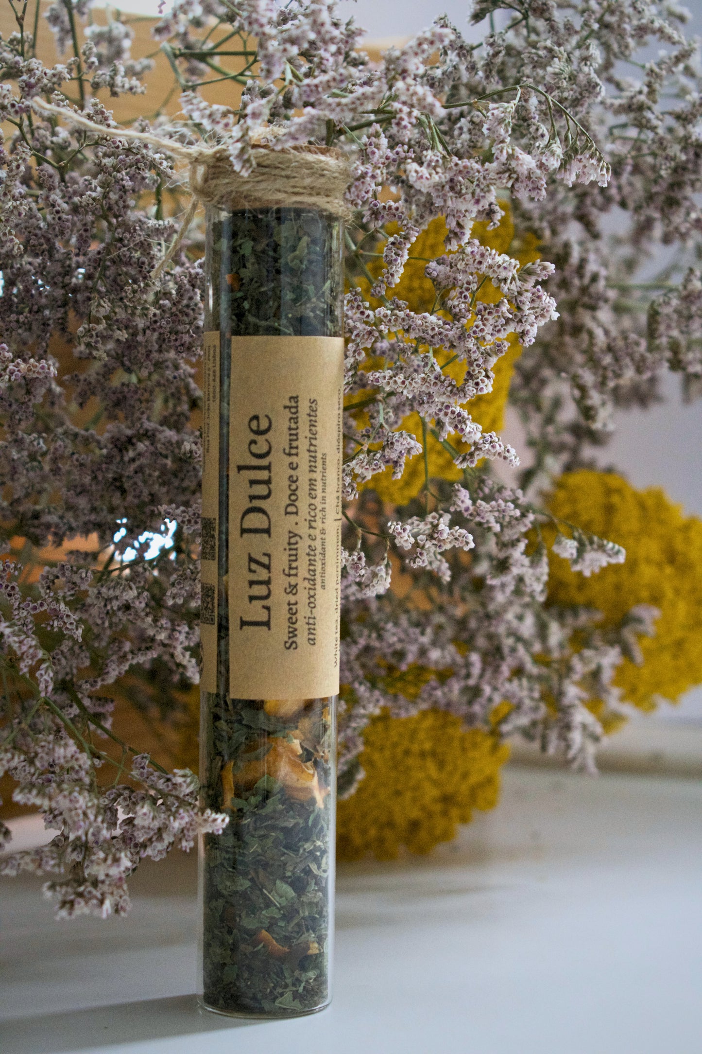 Luz Dulce in a glass tube on a floral background.