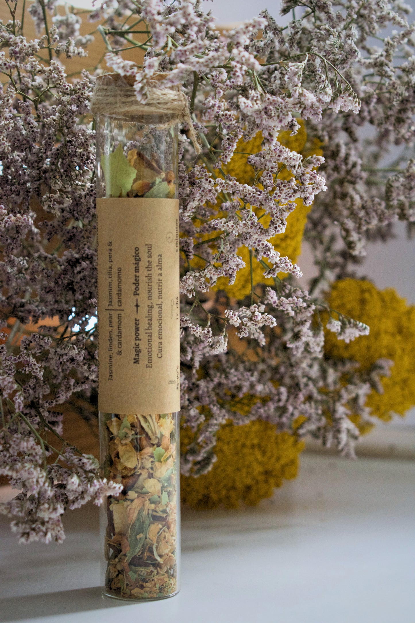Jardim Sereno loose leaves tea in a glass tube on a floral background.