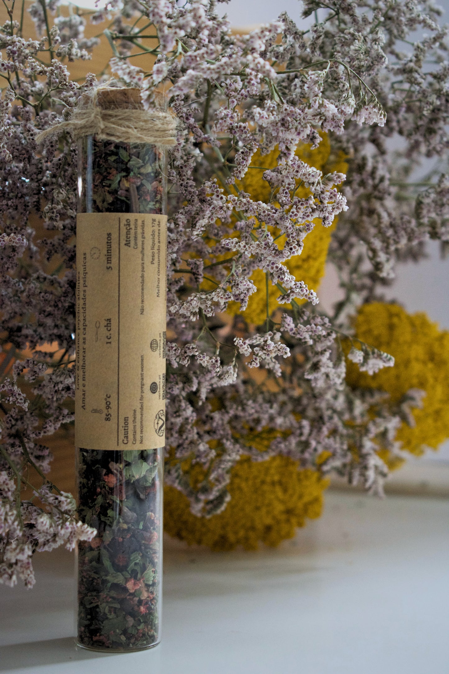 Amor tea blend in a glass tube on a floral background.
