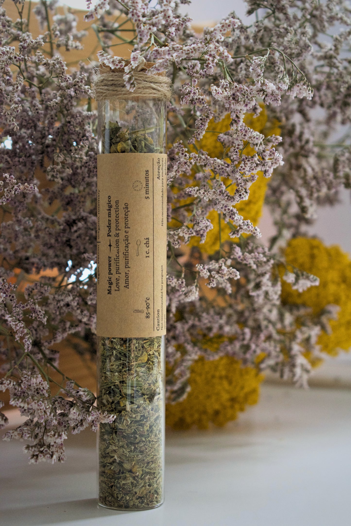 Herbal product in a glass tube labeled 'Moon Cycle' with flowers in the background