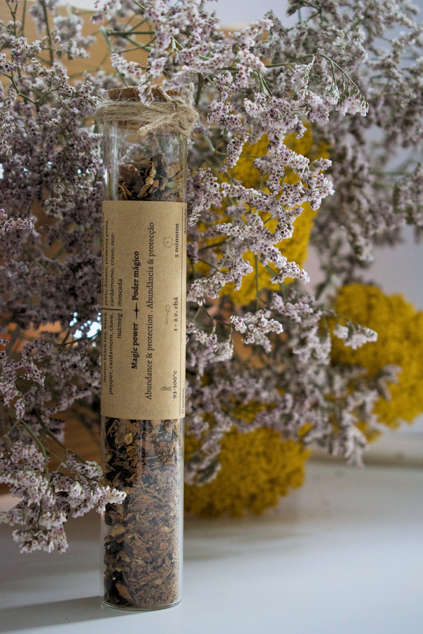 Glass tube with tea blend and spices against a floral background