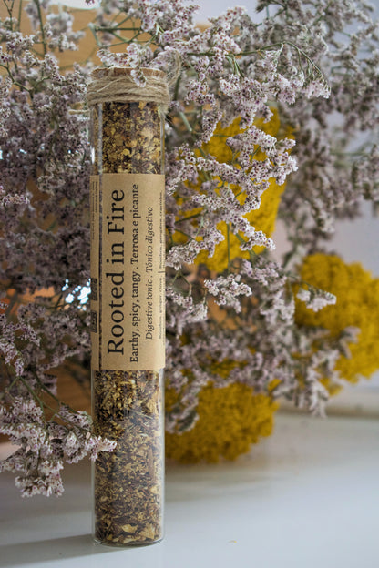 Glass tube with Rooted in fire on floral background.