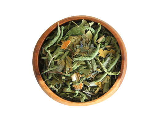 A top-down image of a wooden bowl filled with dried green and yellow herbal tea leaves.